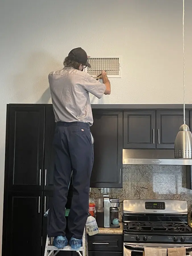 Technician inspecting an air vent during HVAC service in Cleburne